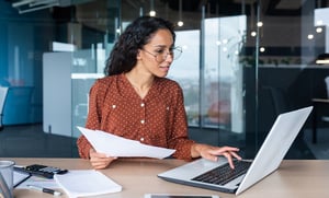 business woman looking at laptop and paperwork